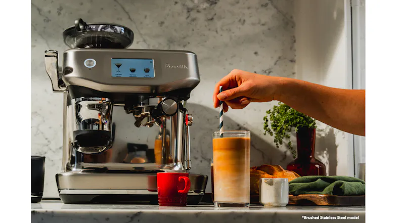 A hand stirs a layered iced coffee. A hand stirs a layered iced coffee.