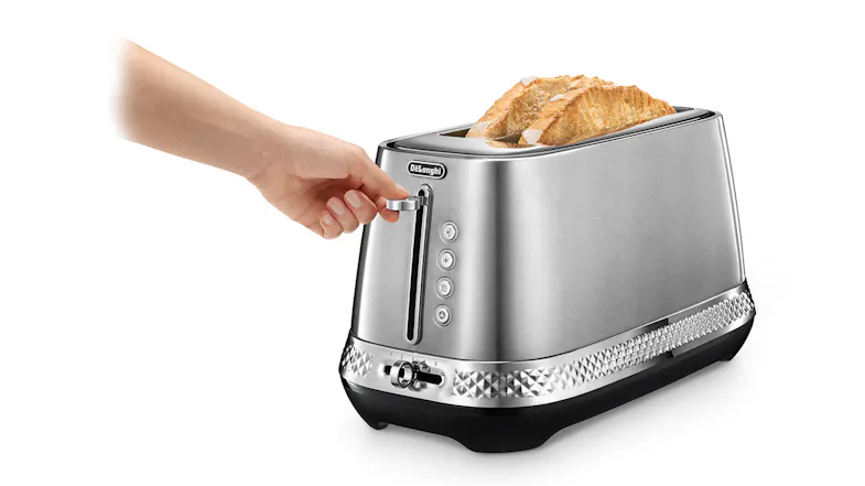 A hand lowers the chrome lever of the platinum toaster while slices of toasted bread protrude from the long slots A hand lowers the chrome lever of the platinum toaster while slices of toasted bread protrude from the long slots