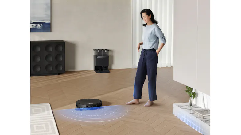 A view of a woman looking at the robot cleaner while it works around the house A view of a woman looking at the robot cleaner while it works around the house