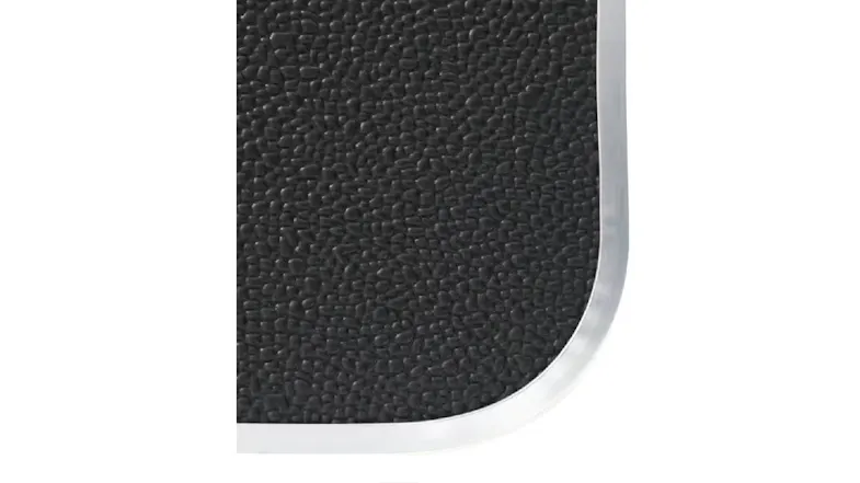 Close-up of a textured black tabletop surface with a rounded corner and a silver trim Close-up of a textured black tabletop surface with a rounded corner and a silver trim