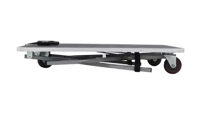 Side view of the table folded flat, showing the compact thickness, folded metal legs underneath, and travel wheels Side view of the table folded flat, showing the compact thickness, folded metal legs underneath, and travel wheels