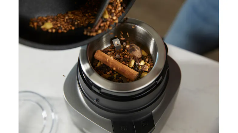 Close-up of whole cinnamon sticks and peppercorns being poured into the grinding bowl Close-up of whole cinnamon sticks and peppercorns being poured into the grinding bowl