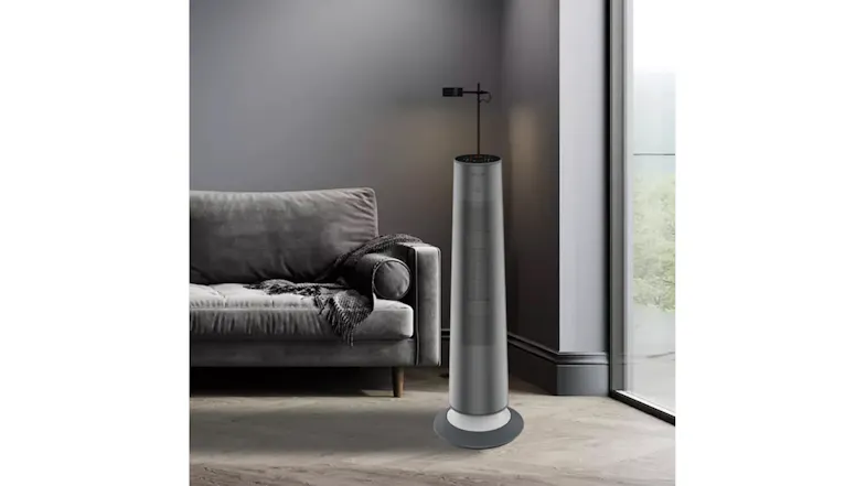 The Goldair graphite tower heater placed in a modern grey living room next to a sofa The Goldair graphite tower heater placed in a modern grey living room next to a sofa