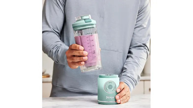 A person holding the blender with pink smoothie A person holding the blender with pink smoothie
