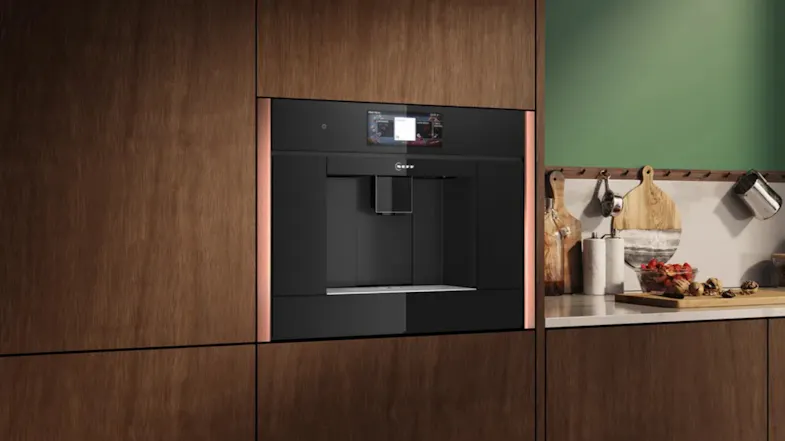 A right-side view of a silver-coloured automatic coffee machine in a built-in kitchen cabinet A right-side view of a silver-coloured automatic coffee machine in a built-in kitchen cabinet