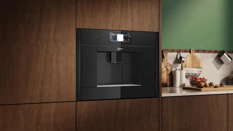 Collection of brushed bronze kitchen appliances, including oven, hood, cooktops, and a built-in coffee machine, displayed on a light surface Collection of brushed bronze kitchen appliances, including oven, hood, cooktops, and a built-in coffee machine, displayed on a light surface