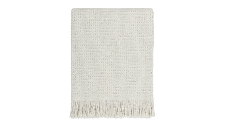 A Celine ecru-coloured waffle weave throw blanket neatly folded, featuring fringed edges A Celine ecru-coloured waffle weave throw blanket neatly folded, featuring fringed edges