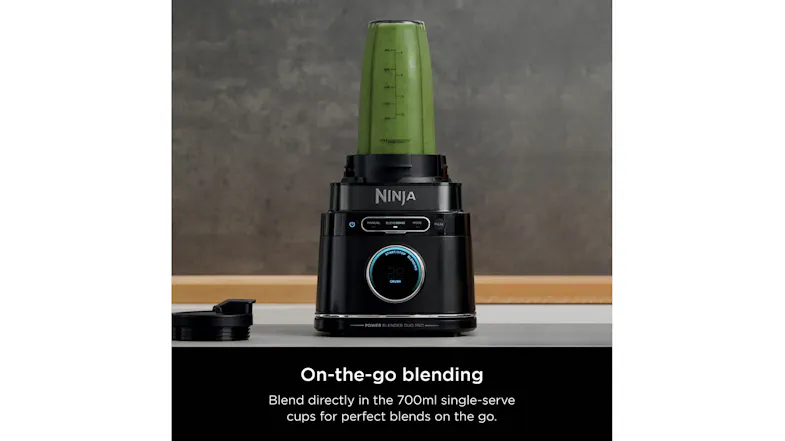 Ninja blender base with a single-serve cup blending a green smoothie on a kitchen counter Ninja blender base with a single-serve cup blending a green smoothie on a kitchen counter