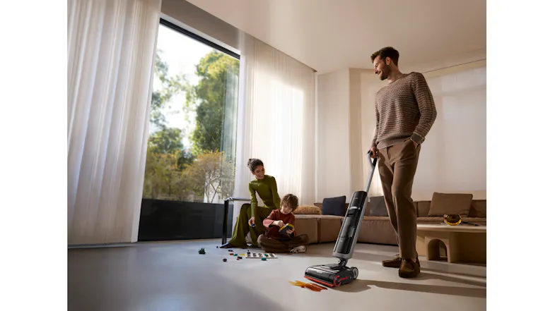 A view of a dad cleaning out a spilled sauce on the floor while a mom is bonding with her son at the back A view of a dad cleaning out a spilled sauce on the floor while a mom is bonding with her son at the back