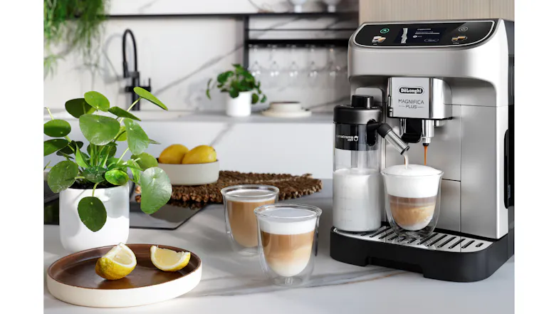 Magnifica Plus espresso machine on a kitchen counter brewing layered lattes with milk frother, cups, and decor nearby Magnifica Plus espresso machine on a kitchen counter brewing layered lattes with milk frother, cups, and decor nearby