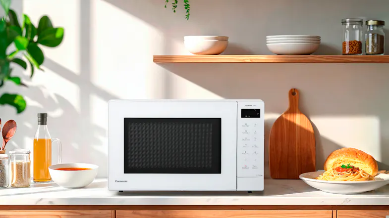 A microwave surrounded by bowls, spices, and a plate of pasta beside a loaf of bread, placed on a kitchen setting A microwave surrounded by bowls, spices, and a plate of pasta beside a loaf of bread, placed on a kitchen setting