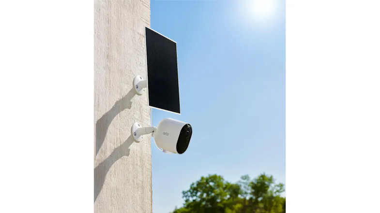 A wall with a security camera and solar panel charger mounted on it. A wall with a security camera and solar panel charger mounted on it.