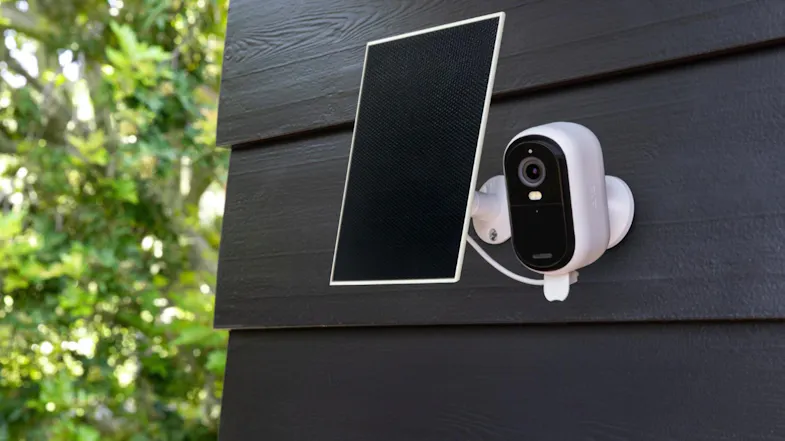 A dark brown siding wall with an Arlo Camera and Solar Charger mounted on it. A dark brown siding wall with an Arlo Camera and Solar Charger mounted on it.