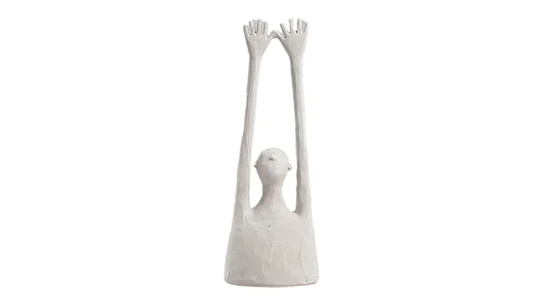 A white small sculpture of a figure with a long torso and arms outstretched towards the sky A white small sculpture of a figure with a long torso and arms outstretched towards the sky