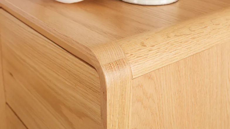 A close-up view of the bedside table’s smooth, rounded corner. A close-up view of the bedside table’s smooth, rounded corner.