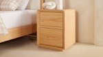A minimalist wooden bedside table with two enclosed drawers. A minimalist wooden bedside table with two enclosed drawers.