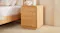 A minimalist wooden bedside table with two enclosed drawers. A minimalist wooden bedside table with two enclosed drawers.