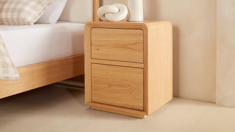 A minimalist wooden bedside table with two enclosed drawers. A minimalist wooden bedside table with two enclosed drawers.