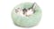 A kitten lies comfortably on a round, fluffy avocado green pet bed. A kitten lies comfortably on a round, fluffy avocado green pet bed.