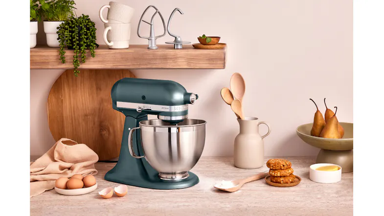 Dark blue-green KitchenAid stand mixer with stainless bowl, surrounded by baking ingredients. Dark blue-green KitchenAid stand mixer with stainless bowl, surrounded by baking ingredients.