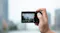 A person using a small digital camera to take a picture of a city. A person using a small digital camera to take a picture of a city.