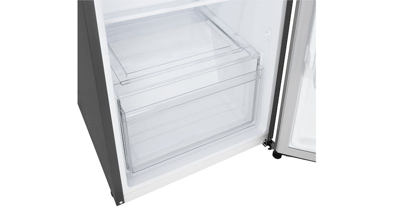 An interior of a refrigerator showing a transparent crisper drawer at the bottom An interior of a refrigerator showing a transparent crisper drawer at the bottom