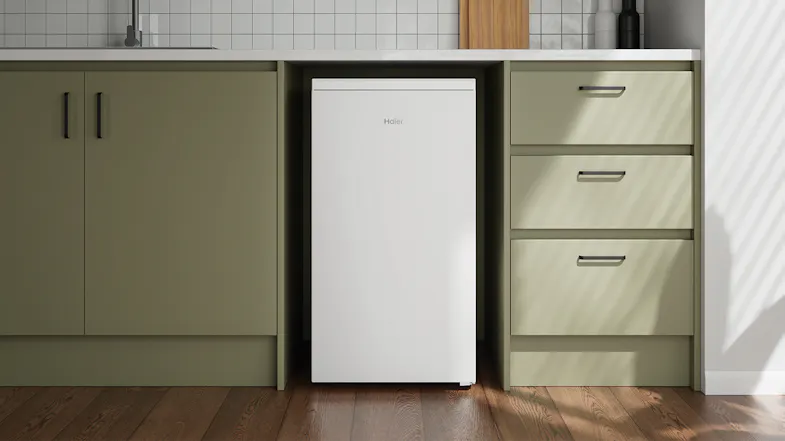 Compact white fridge positioned under green cabinetry Compact white fridge positioned under green cabinetry