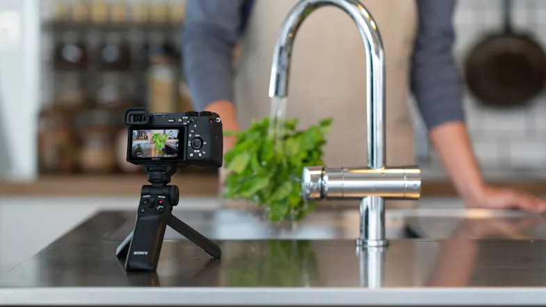 Person vlogging in kitchen using a camera on the Sony grip in tripod mode Person vlogging in kitchen using a camera on the Sony grip in tripod mode