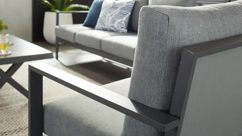 Detailed view of a grey cushioned armchair, showing its metal frame Detailed view of a grey cushioned armchair, showing its metal frame