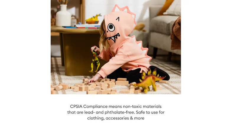 A child in a dinosaur hoodie plays with blocks and toys A child in a dinosaur hoodie plays with blocks and toys