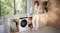 Person holding freshly dried clothes beside Miele dryer in a bright laundry room with wood cabinetry Person holding freshly dried clothes beside Miele dryer in a bright laundry room with wood cabinetry