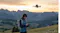 Drone operator at sunset surrounded by hills and distant mountains Drone operator at sunset surrounded by hills and distant mountains