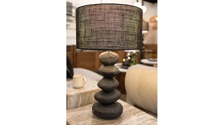A black stacked sphere lamp placed on a wooden table A black stacked sphere lamp placed on a wooden table