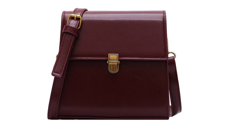 A maroon leather crossbody bag with a gold buckle and an adjustable strap A maroon leather crossbody bag with a gold buckle and an adjustable strap