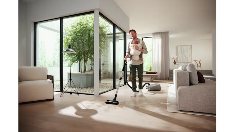 Person vacuuming debris on a wooden floor in a modern space with large windows Person vacuuming debris on a wooden floor in a modern space with large windows