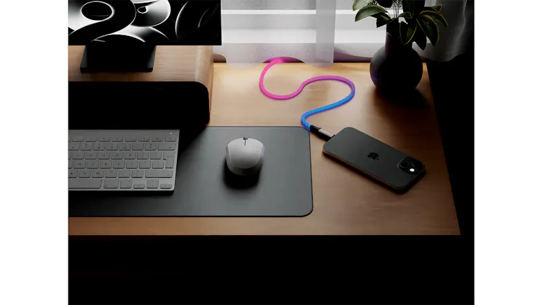 Pink-blue glowing cable connected to a smartphone on a desk Pink-blue glowing cable connected to a smartphone on a desk