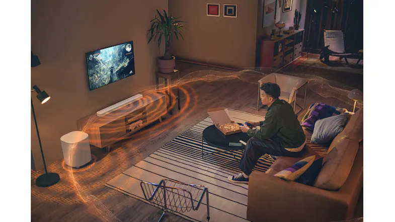 A soundbar emits waves as a person games in a cosy room A soundbar emits waves as a person games in a cosy room