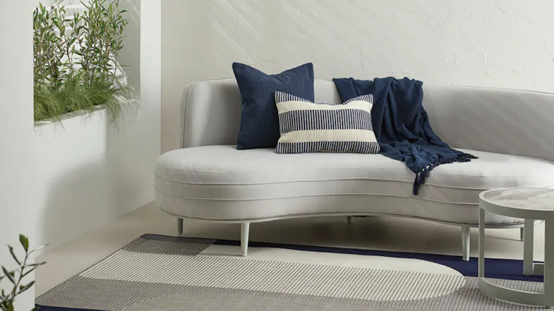 Cushion with textured fabric in navy blue and white tones, placed on a modern sofa. Cushion with textured fabric in navy blue and white tones, placed on a modern sofa.
