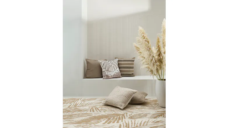 Neutral-toned cushions on a white bench with a beige rug and pampas grass in a vase in front. Neutral-toned cushions on a white bench with a beige rug and pampas grass in a vase in front.