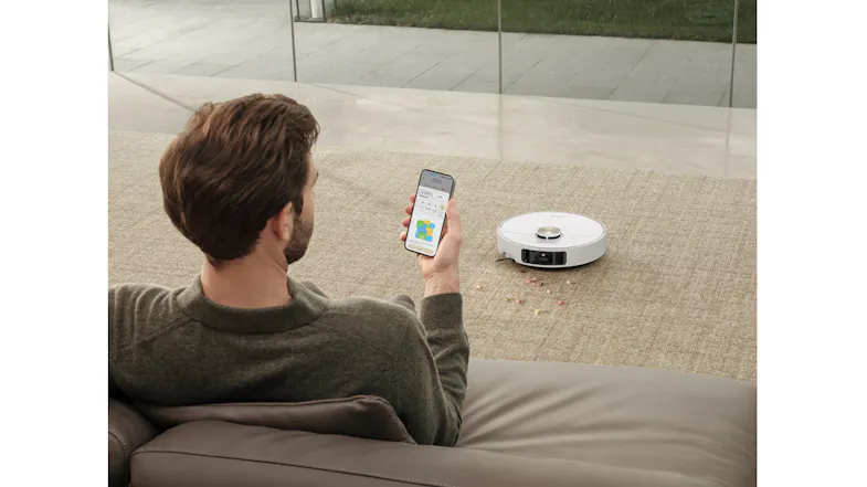 A person using the Dreame app to control the robot vacuum's cleaning while relaxing on the couch A person using the Dreame app to control the robot vacuum's cleaning while relaxing on the couch