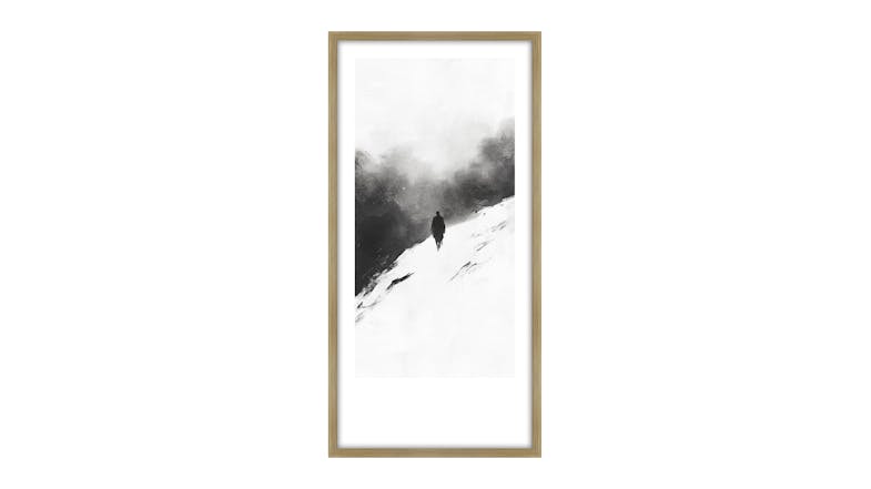 A framed black and white painting depicting a solitary figure walking up a snowy hill with dark clouds in the background. A framed black and white painting depicting a solitary figure walking up a snowy hill with dark clouds in the background.