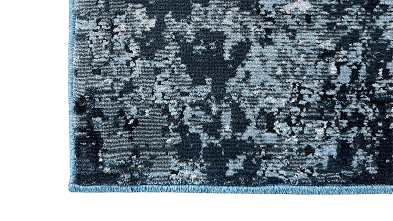 Close-up of rug corner with blue and grey abstract design. Close-up of rug corner with blue and grey abstract design.