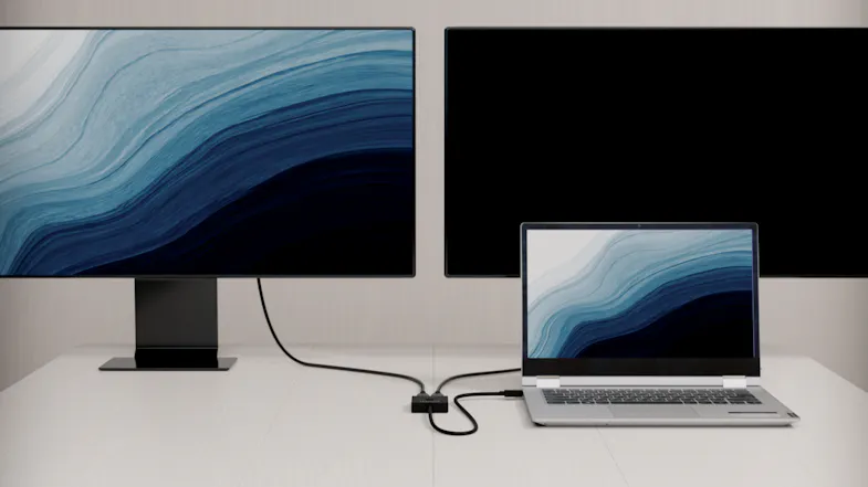 A laptop with dual monitors and a USB-C adapter on the desk A laptop with dual monitors and a USB-C adapter on the desk