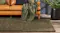 Leather sofa with green and navy cushions, green throw on armrest, and olive Aria rug on wooden floor Leather sofa with green and navy cushions, green throw on armrest, and olive Aria rug on wooden floor