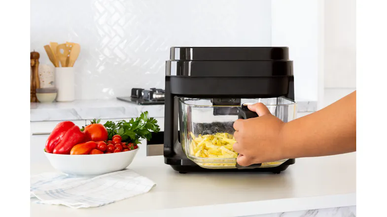 Hand pulling out the air fryer basket filled with golden fries, showing easy handling Hand pulling out the air fryer basket filled with golden fries, showing easy handling