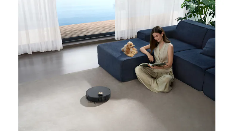 Vacuum cleaning quietly near a person reading and a dog in a living room Vacuum cleaning quietly near a person reading and a dog in a living room