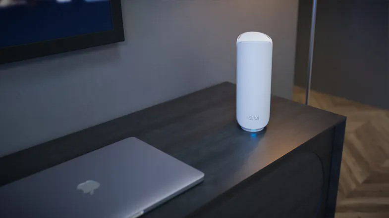 Orbi and MacBook on a wood surface with a herringbone floor Orbi and MacBook on a wood surface with a herringbone floor