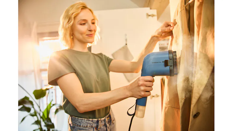 Person in a green shirt using a handheld steamer Person in a green shirt using a handheld steamer