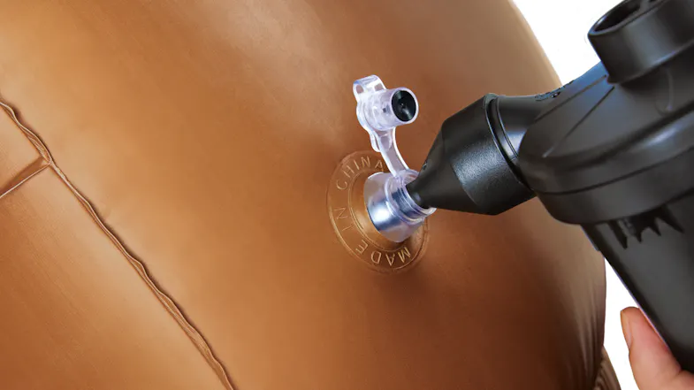 Close-up of a brown bumper ball being inflated with a black air pump attached to its valve Close-up of a brown bumper ball being inflated with a black air pump attached to its valve