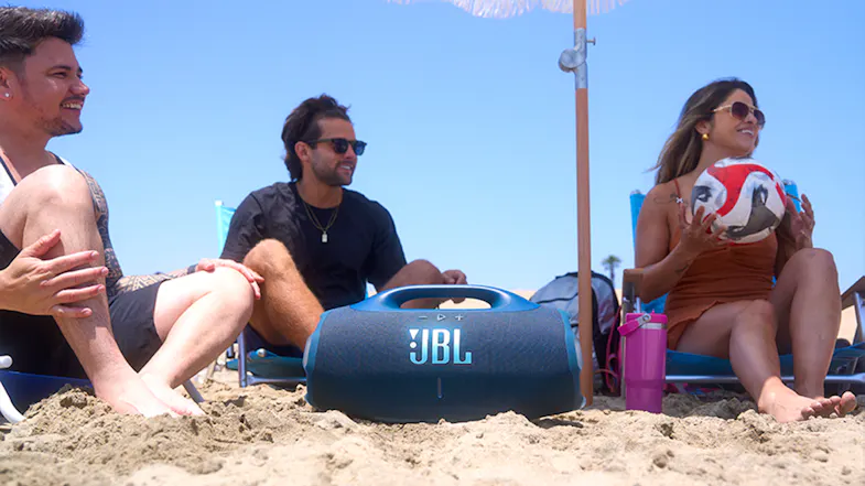 JBL speaker at the beach with three people, a soccer ball, and a pink tumbler JBL speaker at the beach with three people, a soccer ball, and a pink tumbler